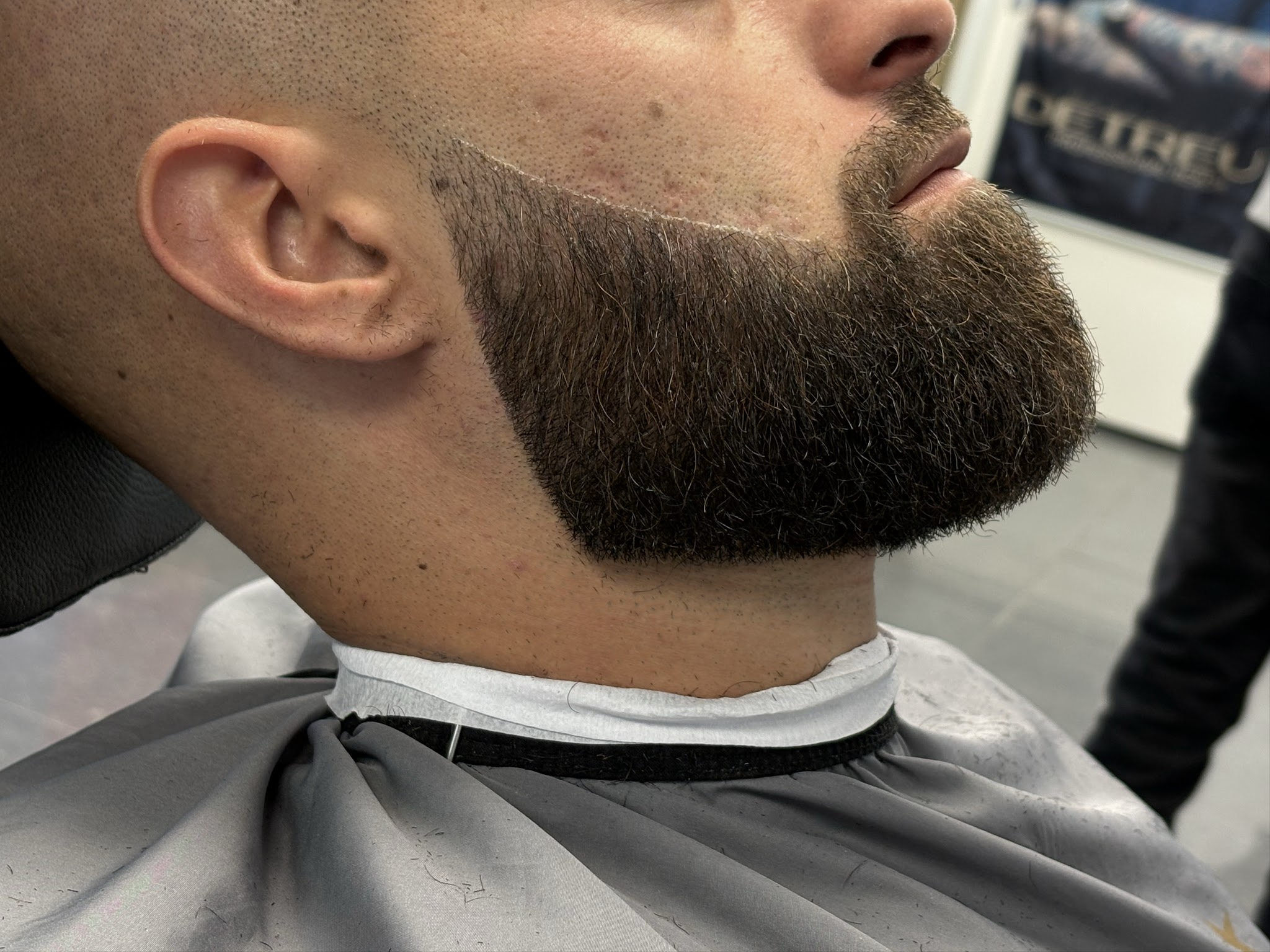 Volle baard met een strakke lijn langs de wang en een fade in de nek